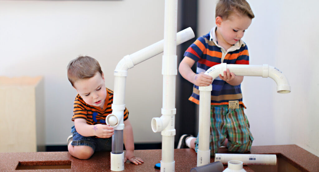 two young boys playing with toy pipes